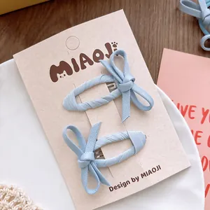 Détail de barrettes à nœuds bleu clair sur carte de présentation pour filles