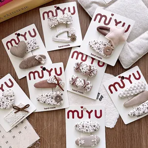 Detail of floral and heart fabric hair clips for girls in warm milk coffee tones