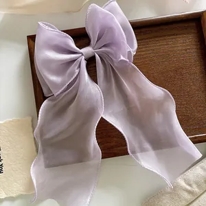 Detail of a large lilac organza bow hair clip with elegant long ribbons on dark wood