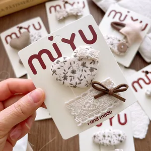 Detail of floral heart fabric clips and lace bow hairpins on handmade card packaging