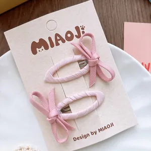 Gros plan de barrettes à nœuds en tissu rose pour filles sur une assiette blanche