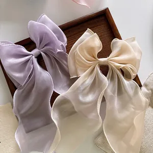 Detail view of large organza bow hair clips with long ribbons in lavender and champagne