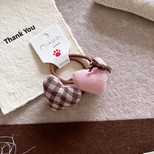 Detailed macro of fabric heart charms on a hair tie in pink and brown checkered patterns