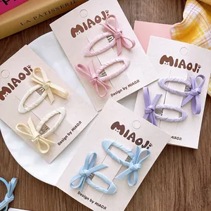 Détail de barrettes à cheveux en tissu pastel avec nœuds sur une carte de présentation