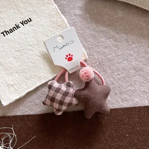 Detail of star-shaped fabric hair ties in plaid and brown with soft plush ball accents