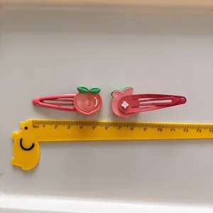 Schattige roze aardbei en beer haarspelden voor meisjes getoond met een liniaal