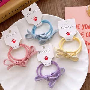 Lot de quatre chouchous nœuds pastel en rose, bleu, jaune et violet sur une carte