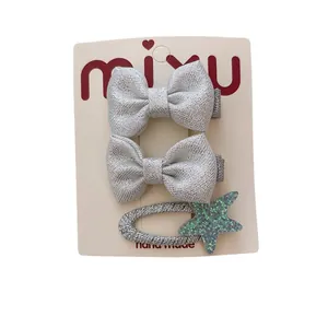 Silver bow hair clips and green glitter star hairpin set on display card