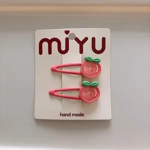 Detail van roze perzik haarspeldjes voor meisjes op displaykaart met groene bladeren
