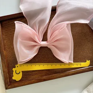 Large pink organza bow hair clip with translucent texture and 14cm oversized design