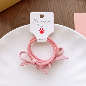 Détail d'un chouchou avec nœud en tissu rose posé sur une assiette en céramique blanche