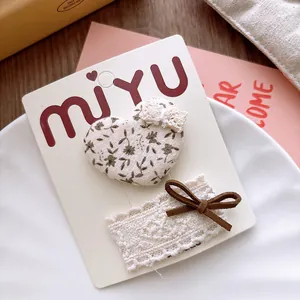Close-up of heart floral fabric hair clip and lace bow set on a white display card