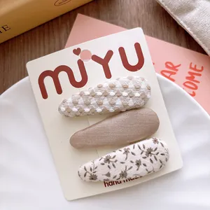 Detailed view of floral and checkered fabric hair clips set on a white brand card