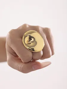 Polished gold circular chunky ring on hand showing a bold minimalist fashion style