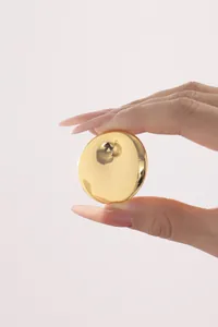 Macro view of a gold-plated mirror finish circular earring component held between fingers