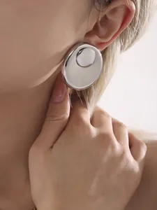 Close-up of oversized silver layered circular earrings on a model for a chic look