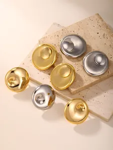 Detailed view of gold and silver metallic oval rings on a minimalist beige stone texture