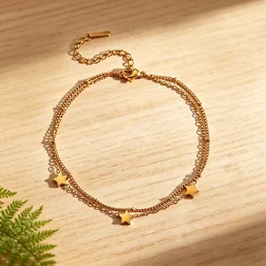 Detailed view of a delicate double-layered gold star anklet placed on a natural wood surface