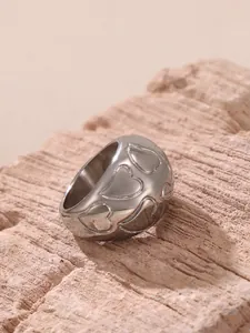 Macro view of wide silver ring band featuring continuous heart pattern engraving