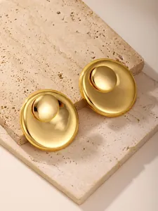 Detailed view of layered gold swirl earrings on a beige stone surface for a vintage look