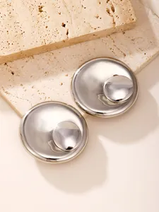 Macro view of silver tone double layer circular stud earrings on stone background