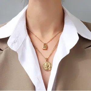 Detailed view of 18K gold layered necklace with square lock and coin pendant on model