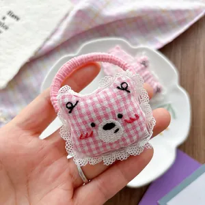 Detail of pink plaid bear hair tie with delicate white lace trim and elastic band