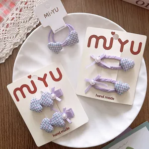Vue détaillée des barrettes cœur violettes et chouchou avec perles et nœuds sur plateau