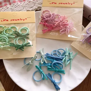 Detailed macro of small candy-colored bow hair ties in a ceramic bowl and packaging