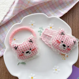 Detail of pink plaid bear hair clip and scrunchie with lace embroidery on a ceramic dish