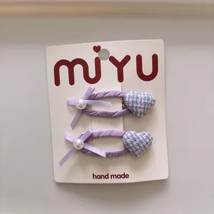 Détail de pinces à cheveux en tissu violet avec cœur et nœud sur carte de support