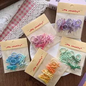 Detail of colorful mini bow hair ties in transparent bags on a rustic wooden background