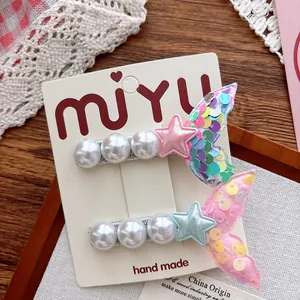 Detail of sequined mermaid tail hair clips with pearls and stars on a display card