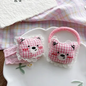 Detail of pink plaid bear hair scrunchies with delicate lace edges and embroidery