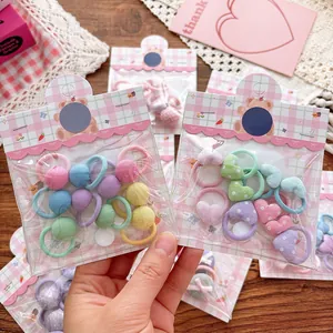 Détails d'élastiques à cheveux colorés avec nœud et cœur sous emballage d'ours