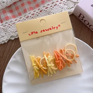 Detail of 10 candy colored mini elastic hair ties in yellow and orange set packaging