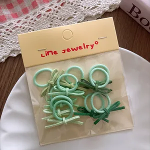 Close-up of small green bow hair ties in assorted shades on a white plate with lace