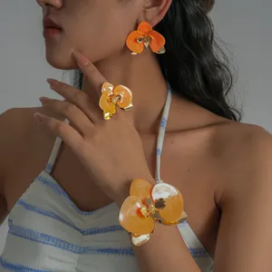Modella elegante che indossa un set di gioielli a fiori in smalto arancione e anello