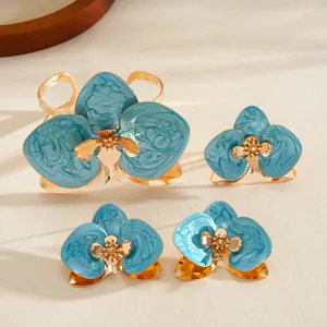 Dettaglio set gioielli fiori smalto blu con bracciale rigido e orecchini placcati oro.