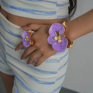 Dettaglio di un bracciale a fiori in smalto viola con anello floreale coordinato