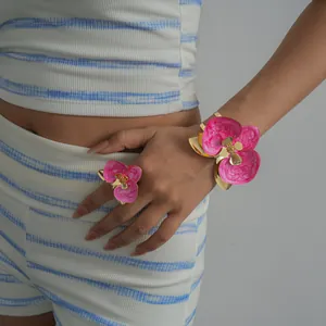 Primo piano di un elegante bracciale a fiore in smalto rosa e set di anelli coordinati