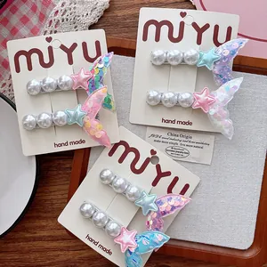 Detail of sequin mermaid tail hair clips with pearls and stars on a white card display