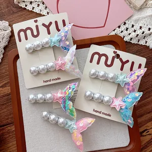 Detail of sequin mermaid tail and pearl hair clip set on a white brand packaging card