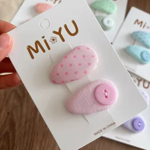 Pink polka dot fabric hair clips for girls featuring button detail and teardrop style