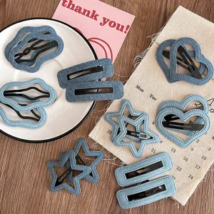 Détail de barrettes en denim bleu en forme d'étoile, de cœur et de nuage sur table bois