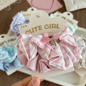 Pink checkered scrunchie with handmade ribbon bow and button on light wood desk