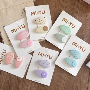 Close-up of colorful polka dot and button fabric drop hair clips on a wooden surface