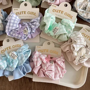 Close-up of colorful checkered scrunchies with ribbon bows and handmade labels