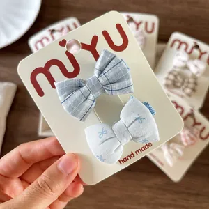 Set of two handmade floral and plaid bow hair clips for girls on display card
