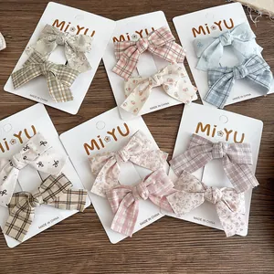 Detail showing various fabric bow hair clips with floral and plaid patterns on cards